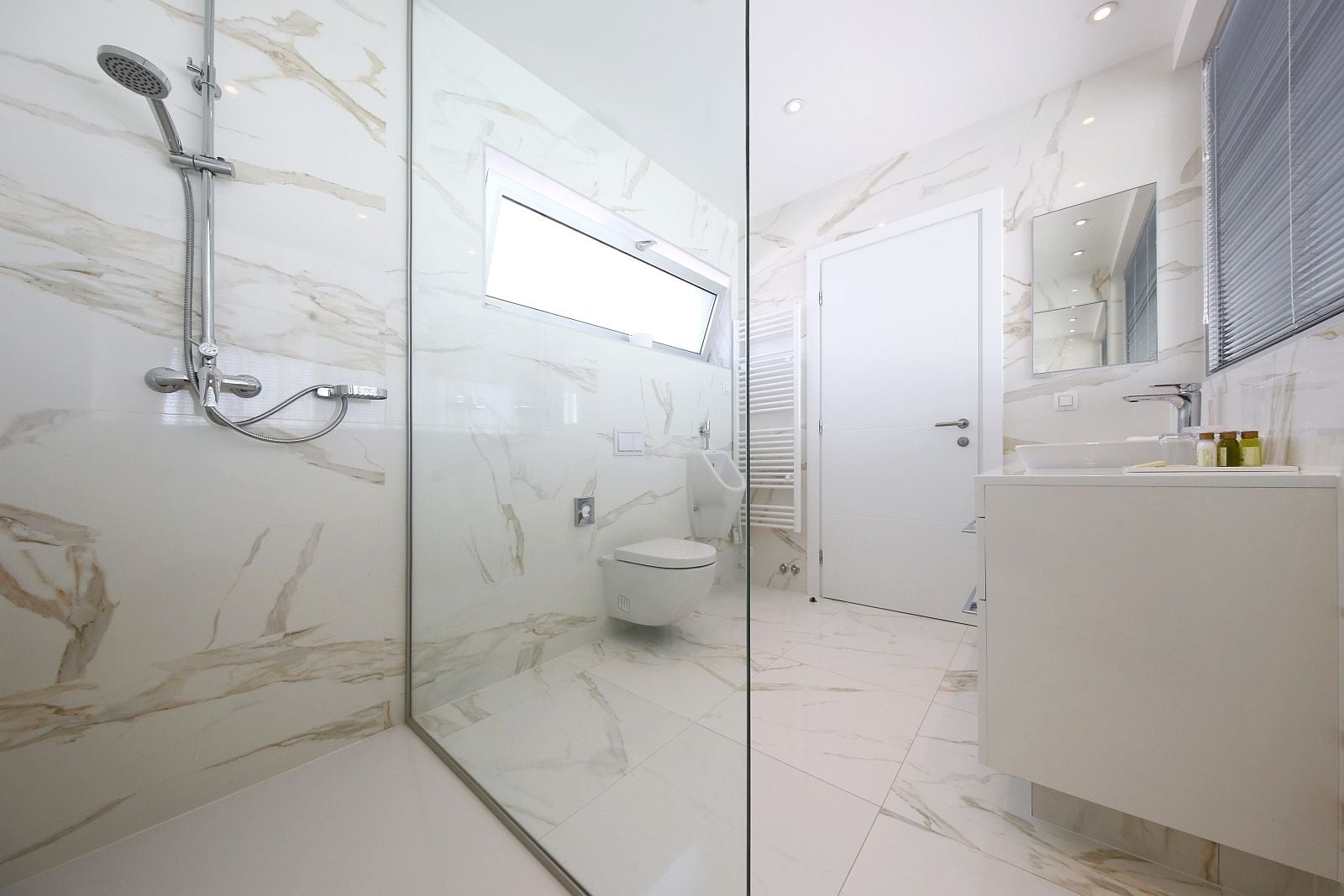 A modern bathroom with a glass-enclosed shower, a toilet, and a vanity with a mirror.