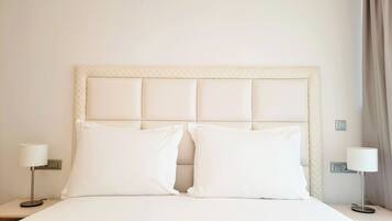 A neatly made bed with a quilted headboard, two bedside tables with lamps, and a power outlet on the wall.