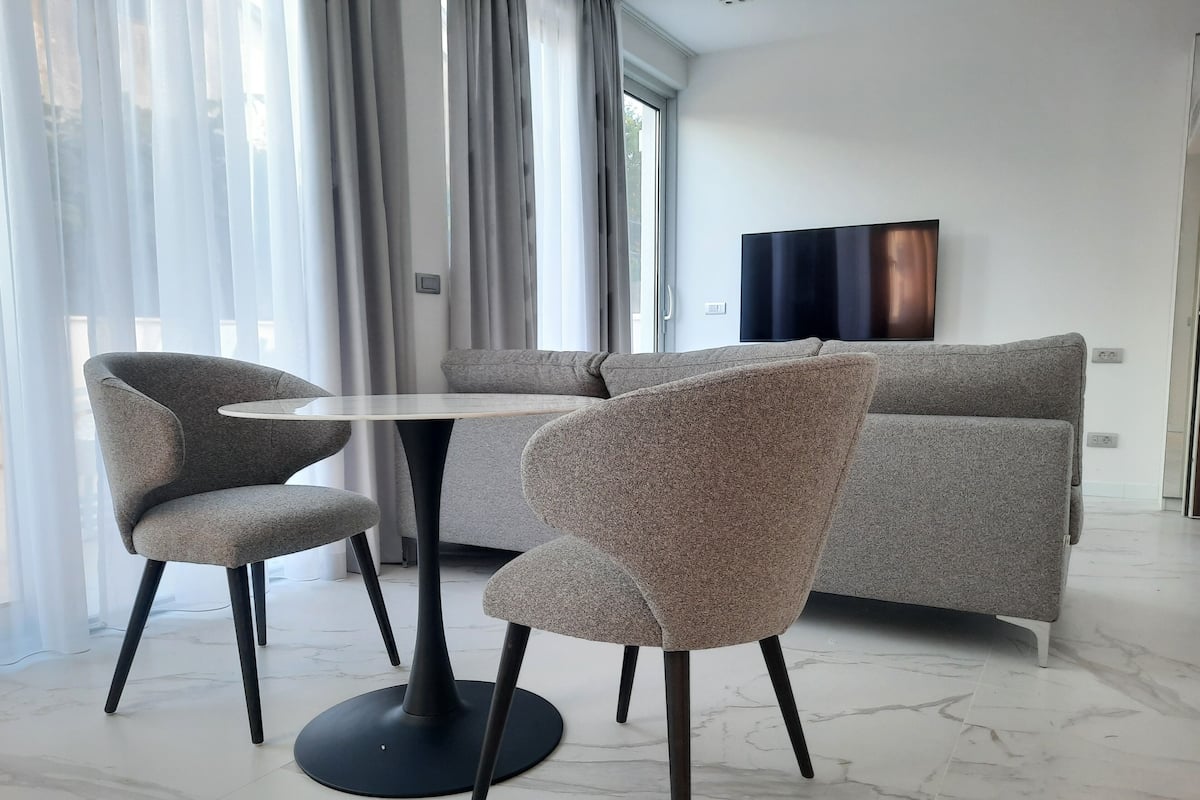 A modern living room with a round table, two armchairs, and a grey sofa.