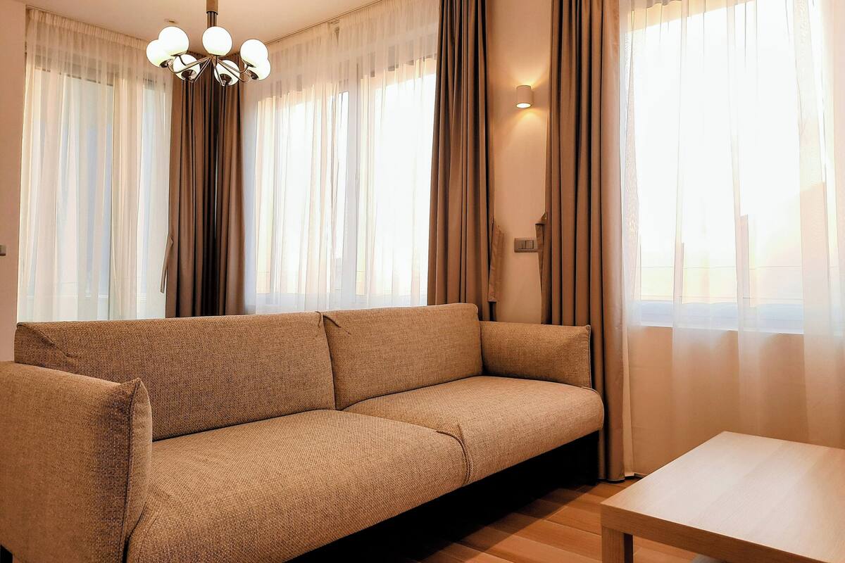 A living room with a sofa, a table, and curtains.