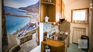 A kitchen with a view of a beach, a sink, and a window with curtains. - Location location location and all the comforts for a charming stay in the Coast (Ravello)