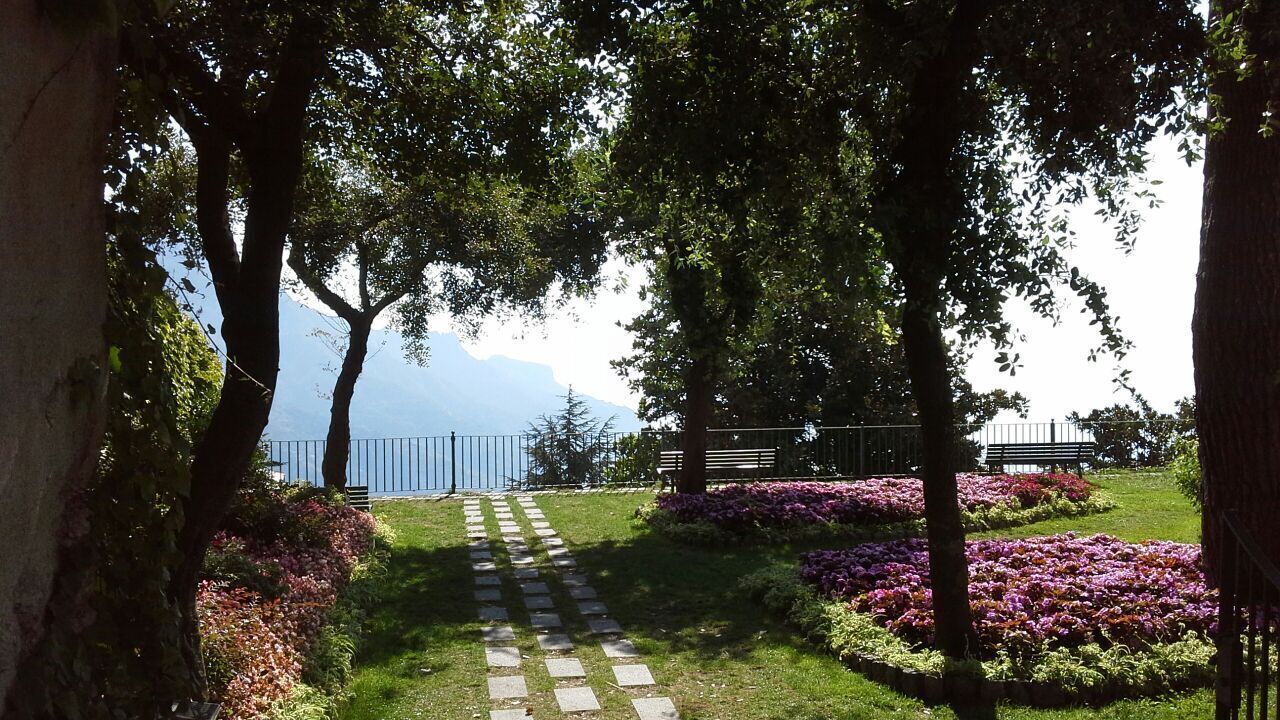 A pathway leading to a bench area with a view of a body of water and mountains in the distance.