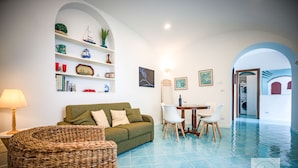 A living room with a green sofa, wicker chair, and a dining area with a table and chairs. - Location location location and all the comforts for a charming stay in the Coast (Ravello)