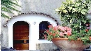 A building with two wooden doors and a large planter with flowers. - Location location location and all the comforts for a charming stay in the Coast (Ravello)