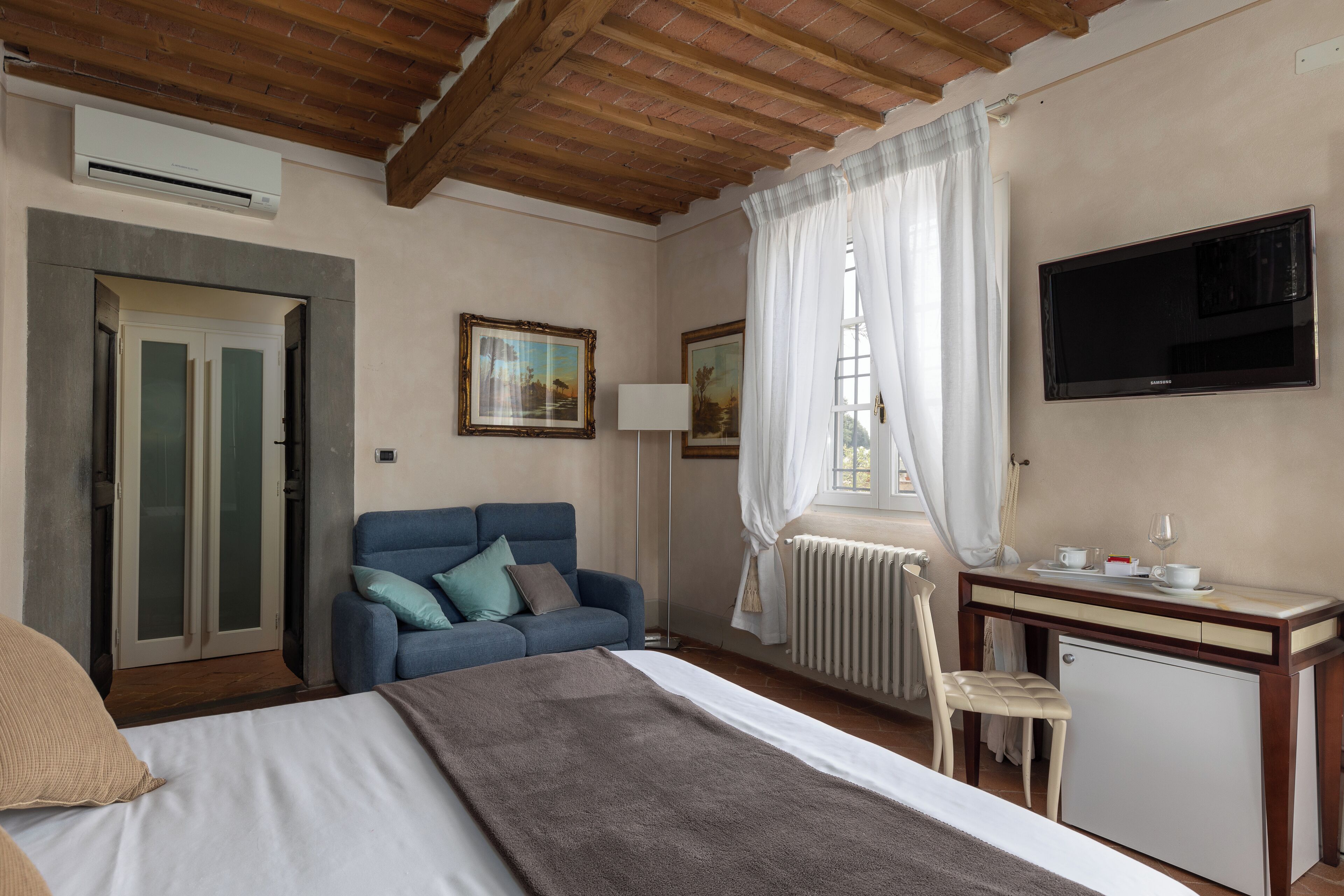 A bedroom with a bed, a desk with a TV, a chair, and a wardrobe.