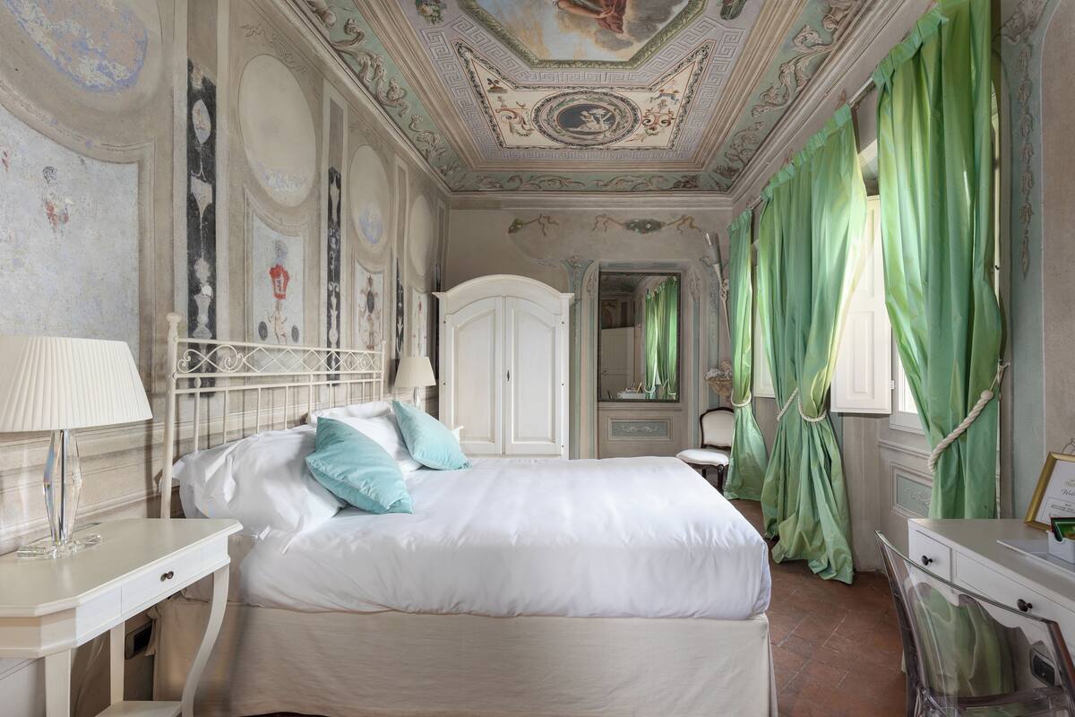 Une chambre à coucher avec un grand lit, une table de chevet, une commode et un miroir.