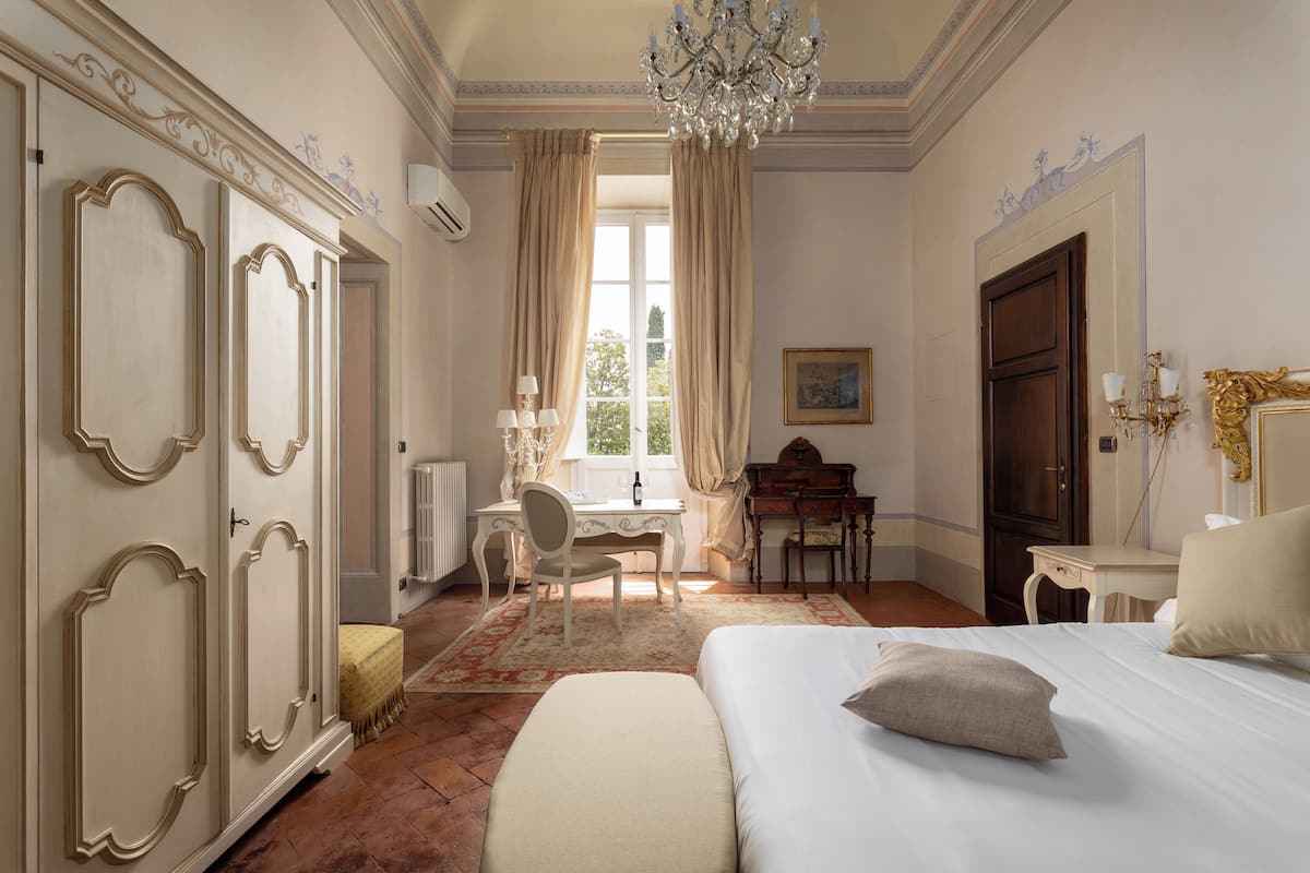 Une chambre avec un grand lit, un bureau, une chaise et un piano.
