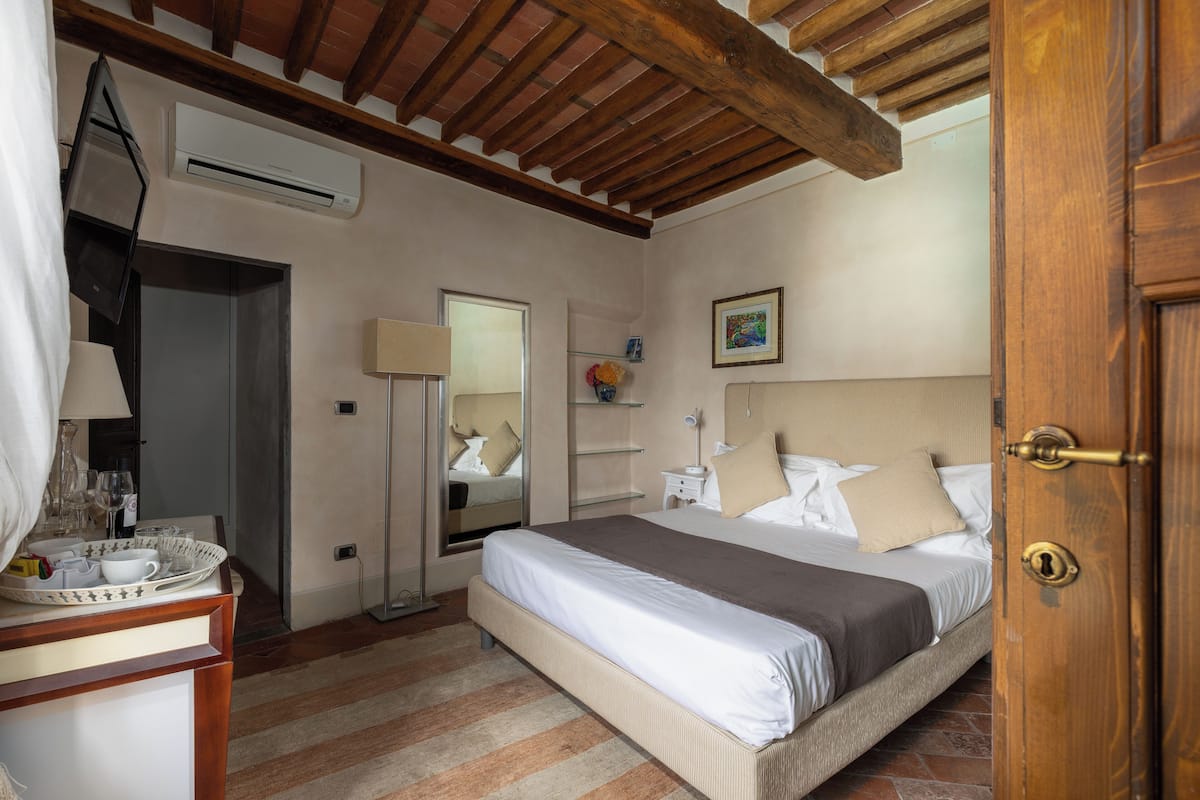 Une chambre à coucher avec un lit, une table de chevet, un miroir et une porte.
