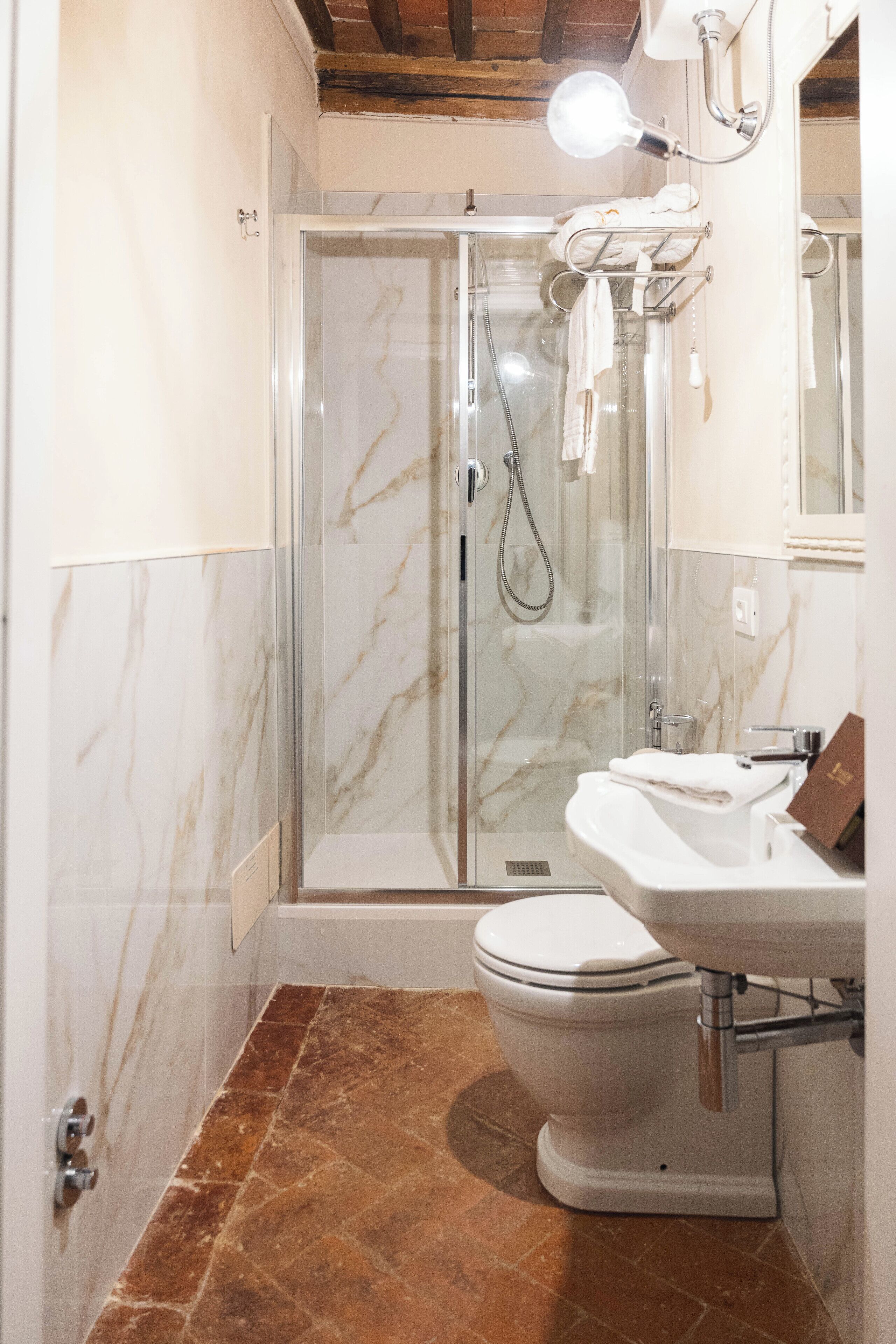 A bathroom with a glass-enclosed shower, a white toilet, and a sink.