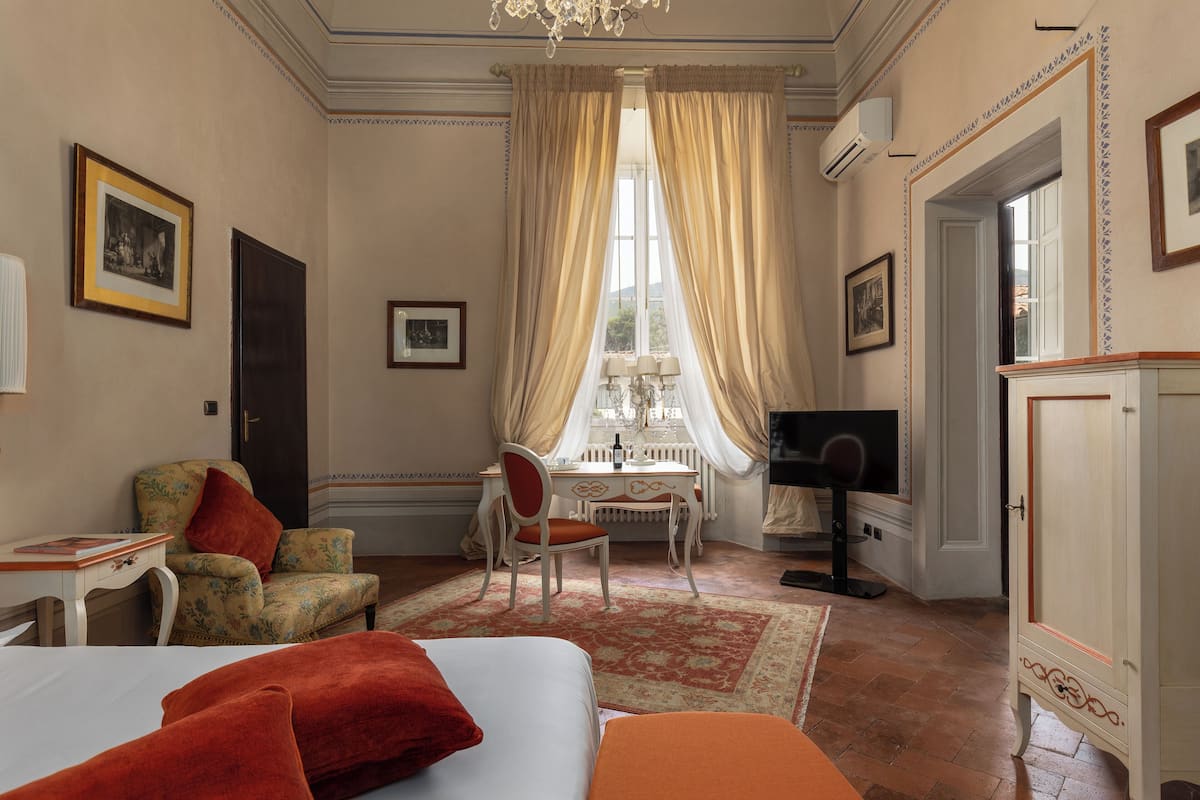 Une chambre d’hôtel comprenant un lit, une chaise, un bureau avec une lampe, une télévision et une armoire.