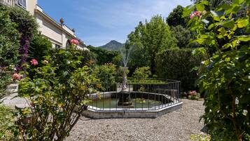 Um jardim com uma fonte, rodeado por cascalho e diversas plantas.