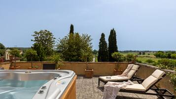 Eine Dachterrasse mit Whirlpool, Liegestühlen und Topfpflanzen.