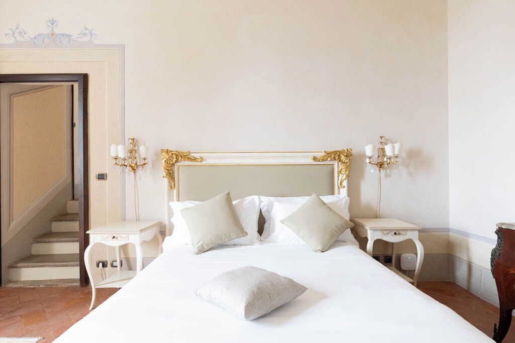 Ein Hotelzimmer mit einem großen Bett, zwei Nachttischen, einer Kandelaber und einer Treppe.