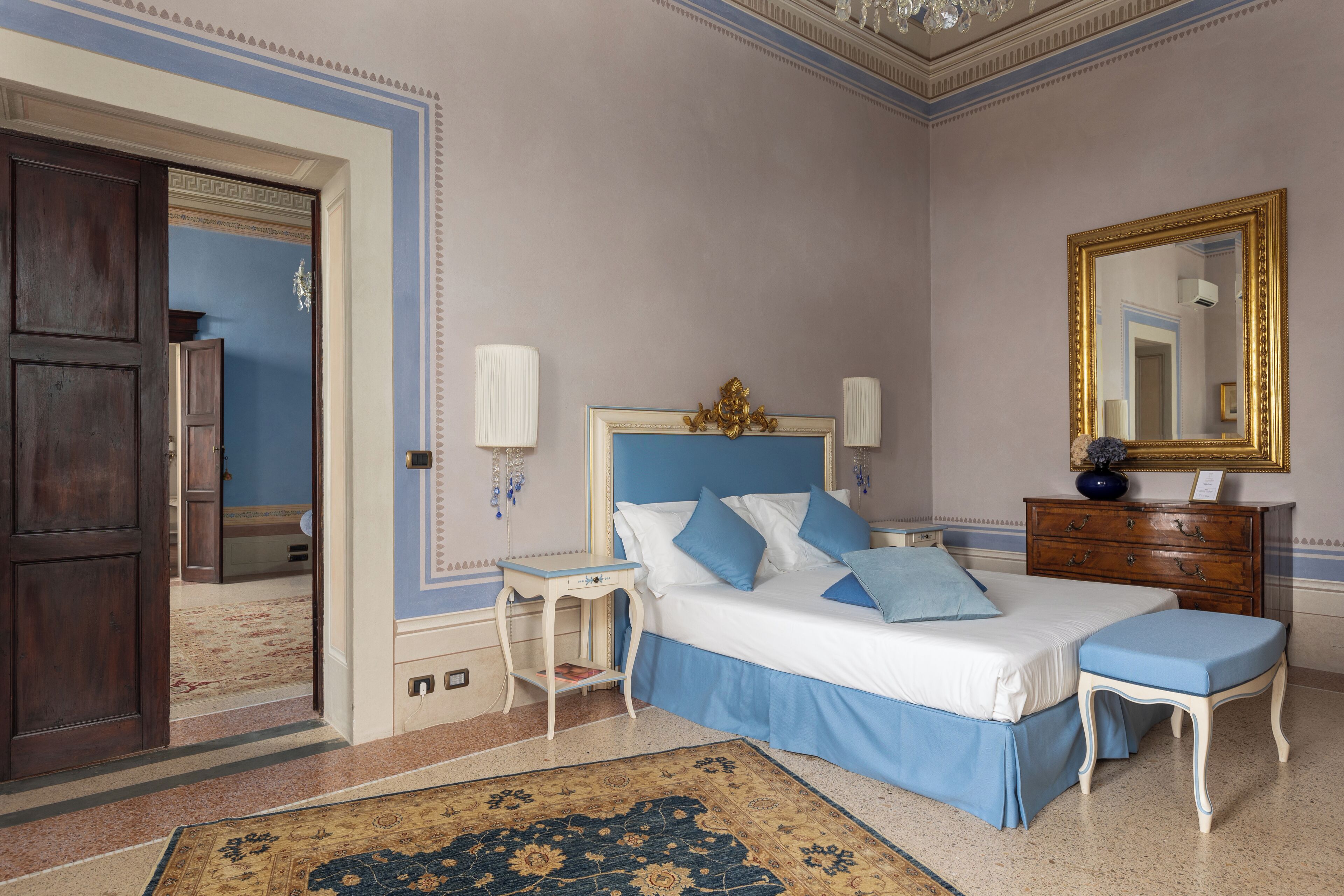 A bedroom with a bed, bedside table, dresser, and a mirror.