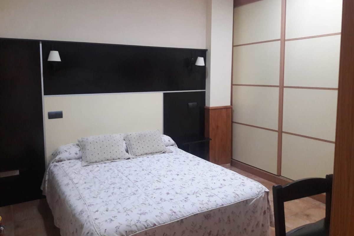 A bedroom with a bed, a wardrobe, and two bedside lamps.