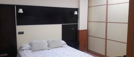 A bedroom with a bed, a wardrobe, and two bedside lamps.