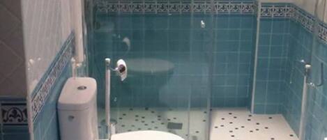 A bathroom with a toilet, a shower enclosure, and blue-tiled walls.