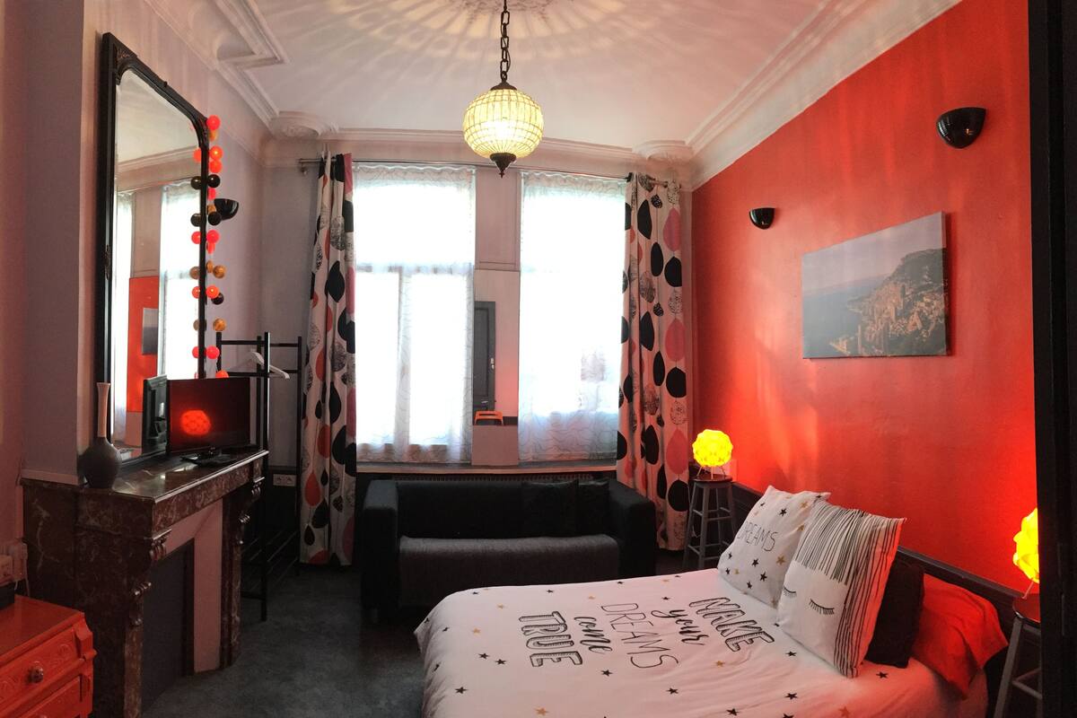 Une chambre à coucher comprenant un lit, une coiffeuse avec un miroir, une commode, un banc et un tableau accroché au mur.