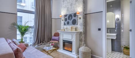 A modern living room with a fireplace, a sofa, a coffee table, and a large window with curtains.