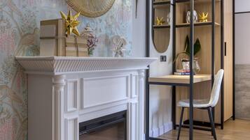 A room with a white fireplace, a mirror above it, and a bookshelf with decorative items.