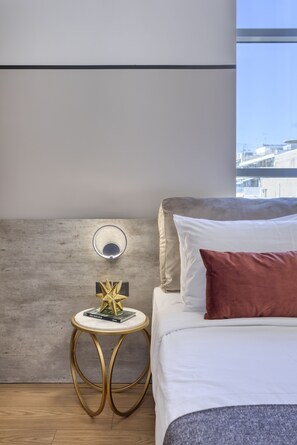 A modern bedroom with a bed, a round side table with a book, and a wall-mounted light.