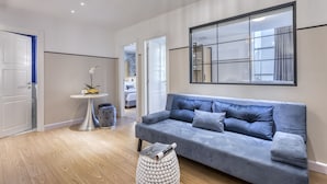 Una sala de estar moderna con un sofá gris, una mesa de centro redonda y un espejo grande en la pared.