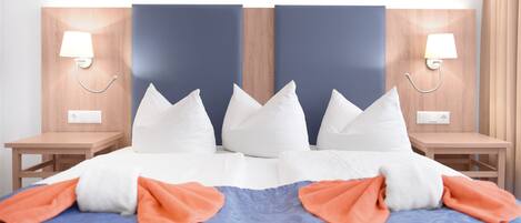 Habitación de hotel con una cama grande, dos mesitas de noche y un cabecero con dos lámparas de pared.