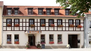 A traditional half-timbered building with flower boxes and a sign for "Gasthof". - Hotel zum Schwan (Beeskow)