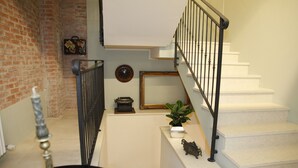 A staircase with a black railing, a potted plant, and a vintage typewriter on the landing. - Juliet's Nest (Verona)