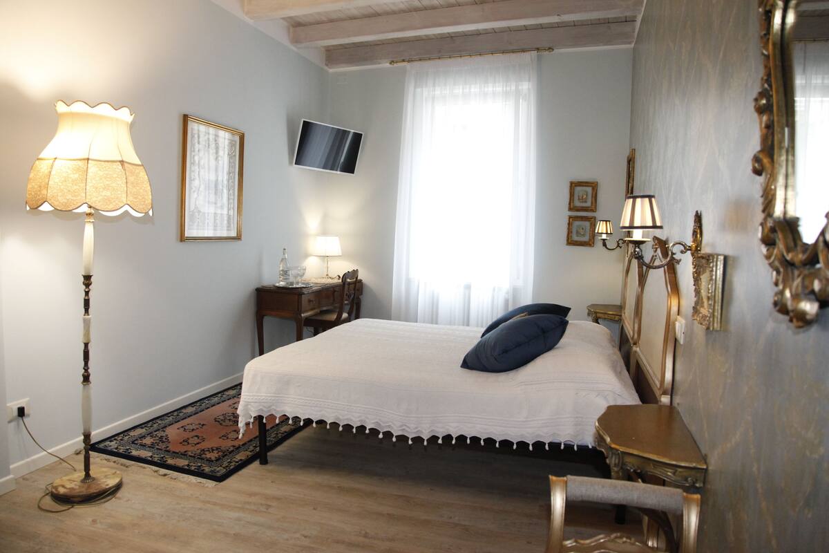Une chambre à coucher comprenant un lit, un bureau, une chaise, une lampe, un téléviseur et un miroir.