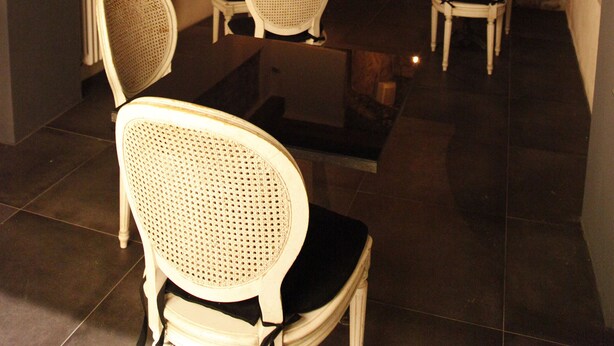 A cozy room with stone walls, wooden beams, and white wicker chairs. - Juliet's Nest (Verona)