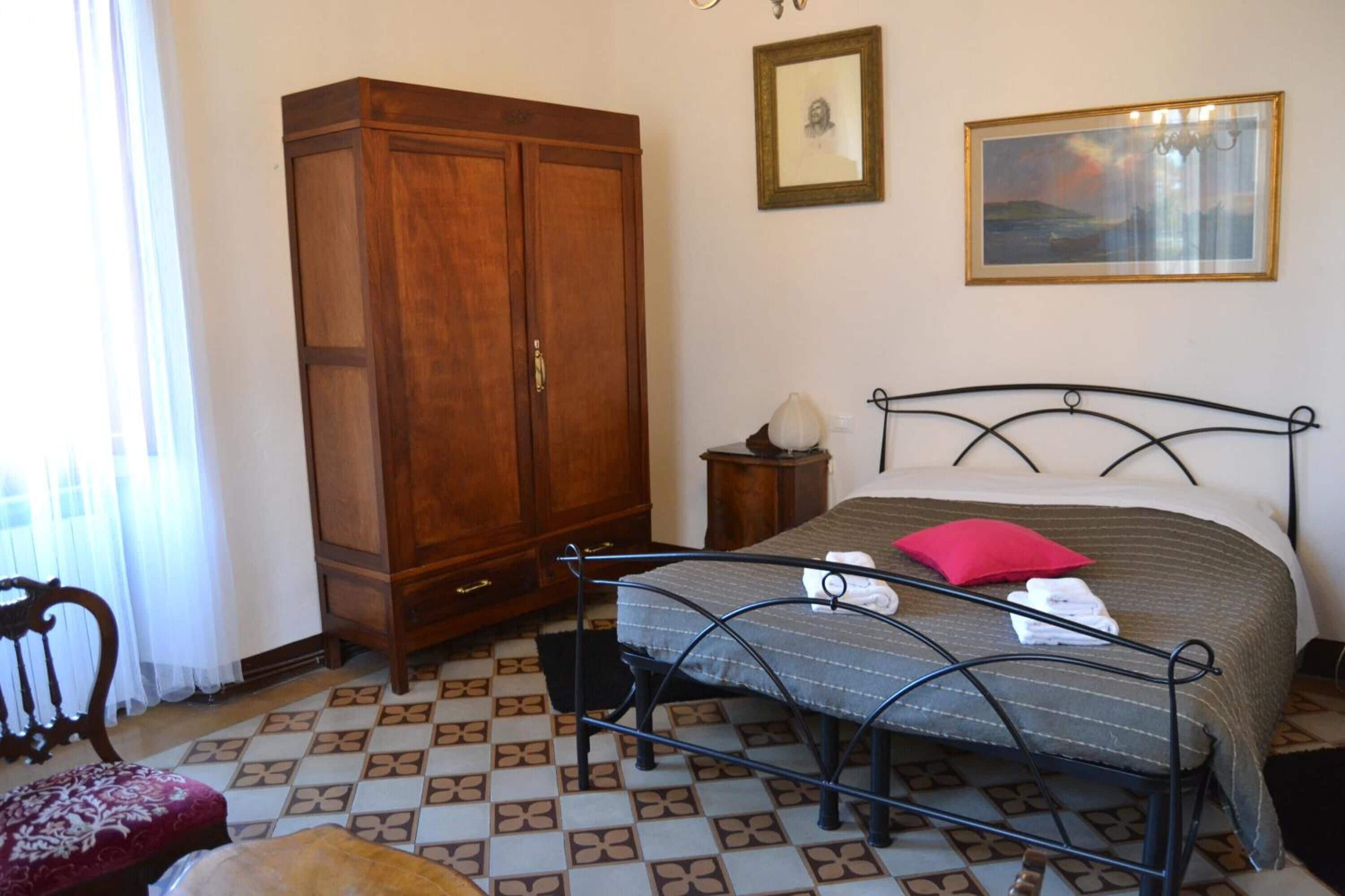 Un dormitorio con cama, armario, una silla y una mesita.