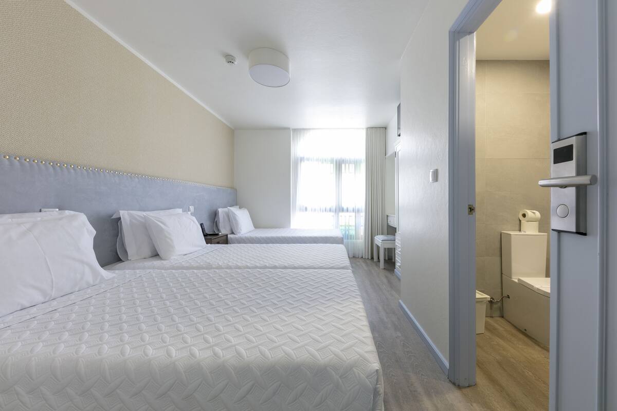 A hotel room with two beds, a bathroom, and a TV.