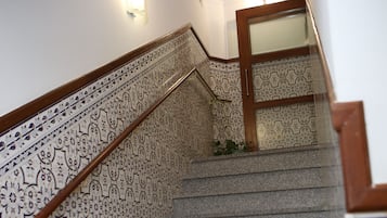 Un escalier avec des rampes décorées et une porte en bois en haut.