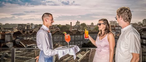 Three people on a rooftop terrace with a cityscape view.