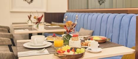 A breakfast setup with a table, chairs, and a blue cushioned bench.