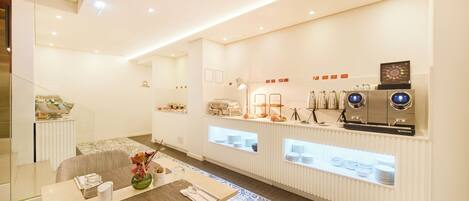 Un hall d’hôtel moderne comprenant un comptoir d’accueil, un espace salon et un coin café.