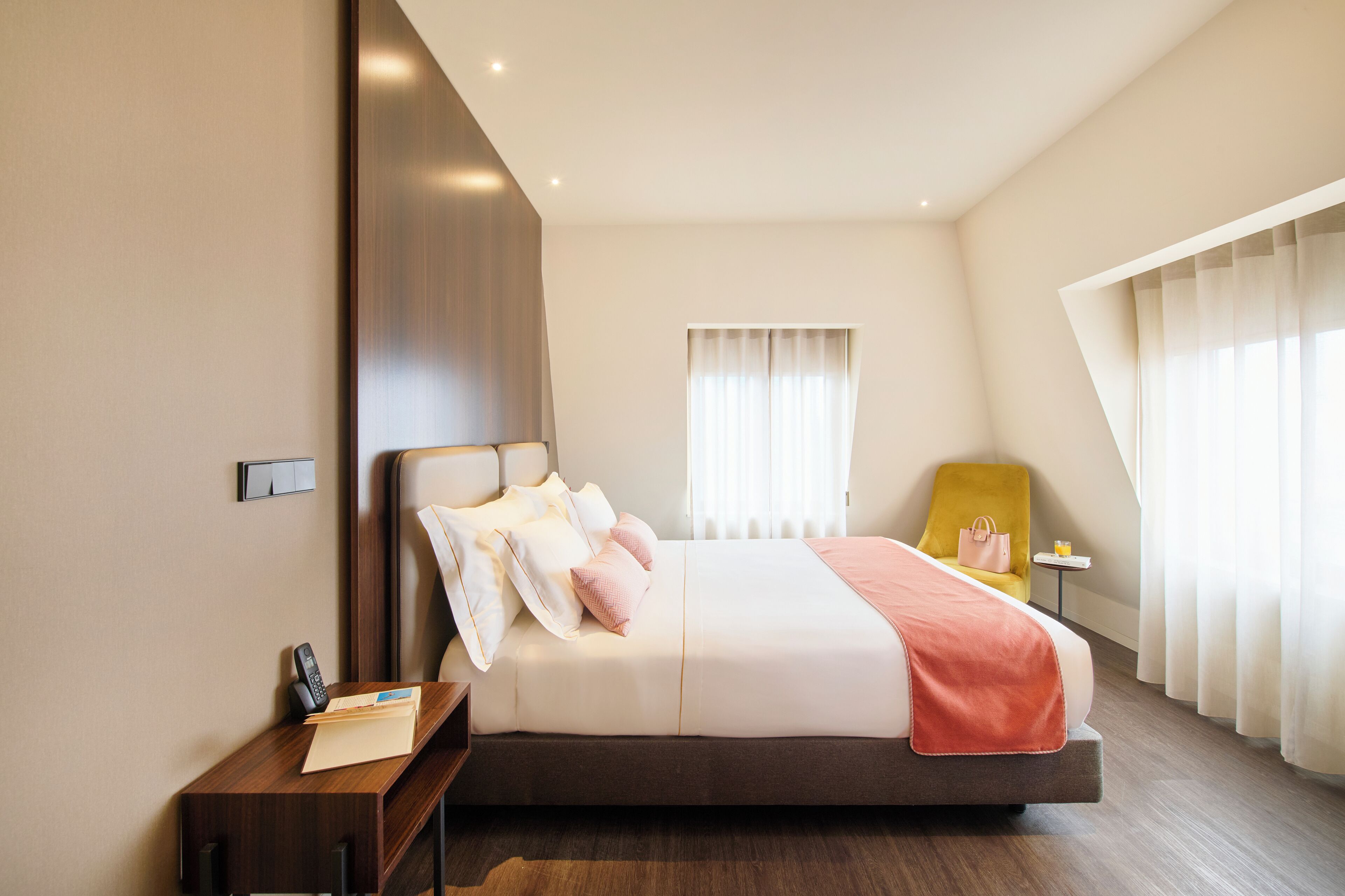 Una habitación de hotel moderna con una cama grande, una mesita de noche y una silla.
