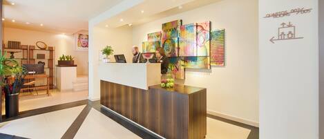 A reception desk with a modern design, a seating area with a table and chairs, and a wall with directional signage.