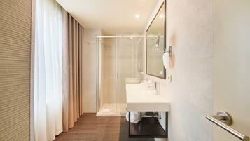 Une salle de bain moderne avec une douche à parois de verre, un lavabo blanc et un grand miroir.