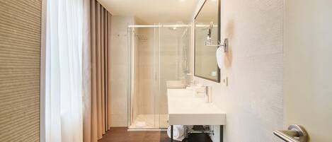 A modern bathroom with a glass shower enclosure, a white sink, and a large mirror.