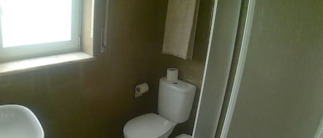 A small bathroom with a toilet, sink, and a towel hanging on the wall.