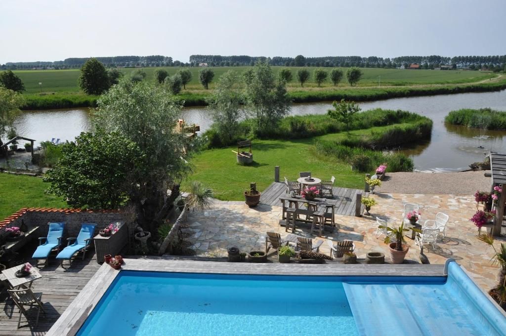 A swimming pool with a deck area, surrounded by a grassy landscape and a river.