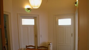 A dining area with a wooden table and chairs, a hanging light fixture, and two doors with windows. - CoLodging (Mannheim)