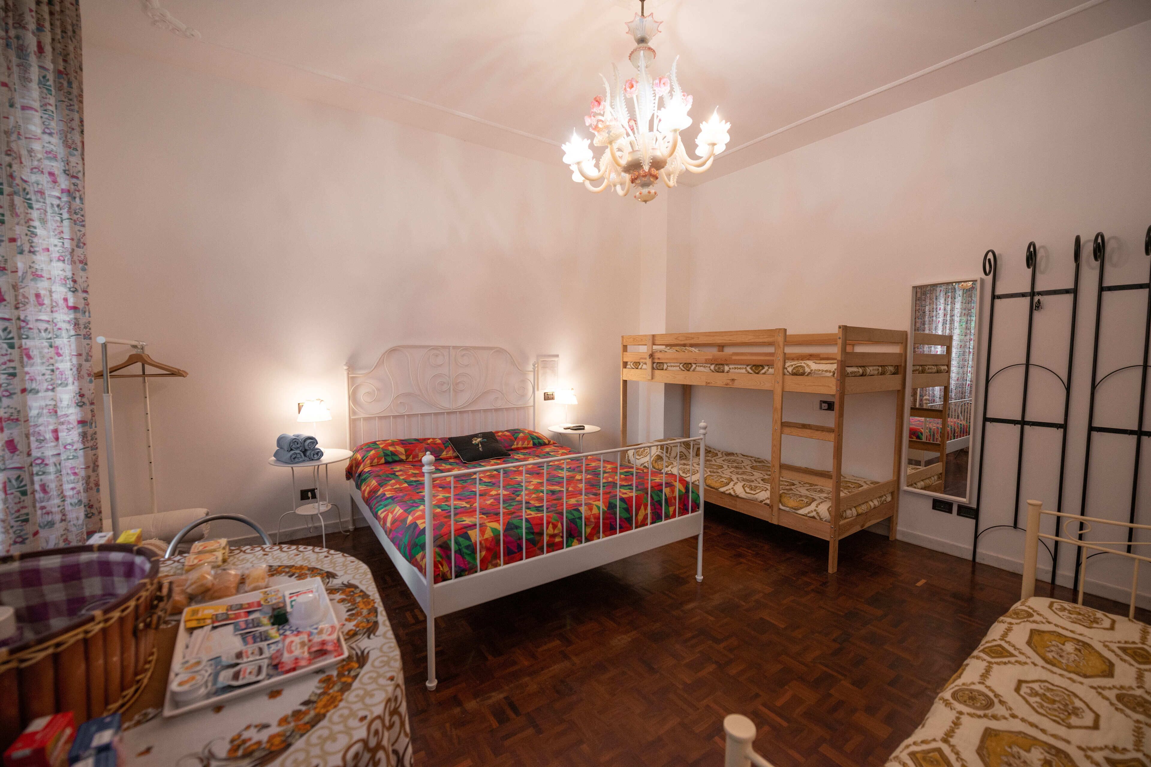 Une chambre avec un lit superposé, une table de chevet avec une lampe, un luminaire suspendu et une armoire.