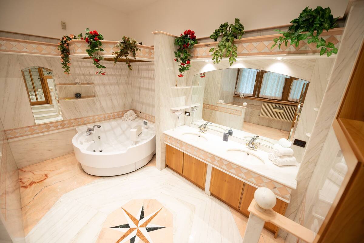 A modern bathroom with a large bathtub, two sinks, and a mirror.