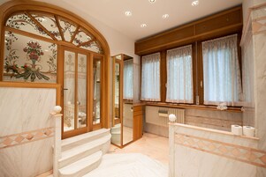 Un bagno con pavimento in marmo, un mobile bagno in legno, uno specchio e una finestra con tende.