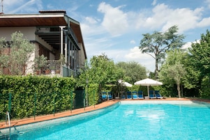 Una piscina al aire libre de temporada, sombrillas, tumbonas