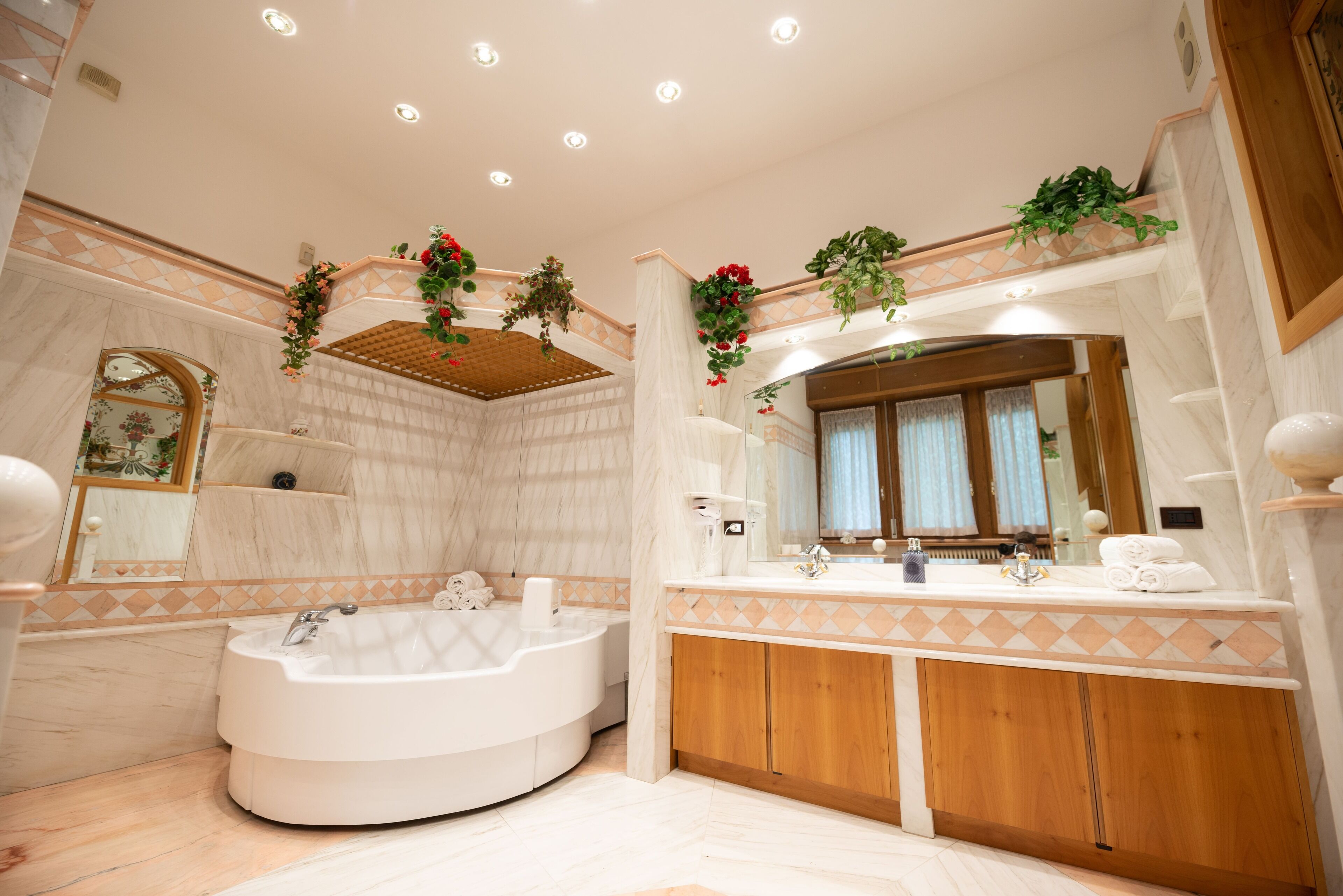 Un baño moderno con una bañera independiente, un espejo grande y armarios de madera.