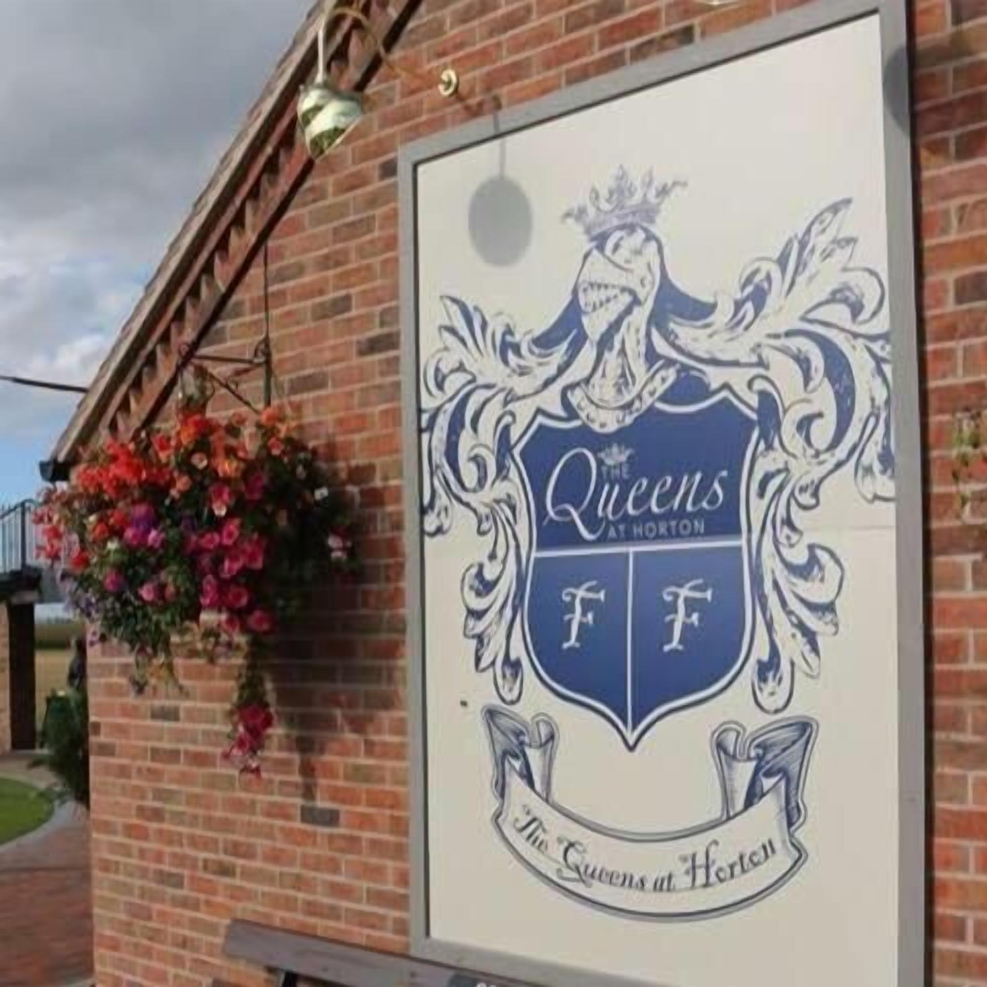 A sign for 'The Queens at Horton' with a crest and the name of the establishment.